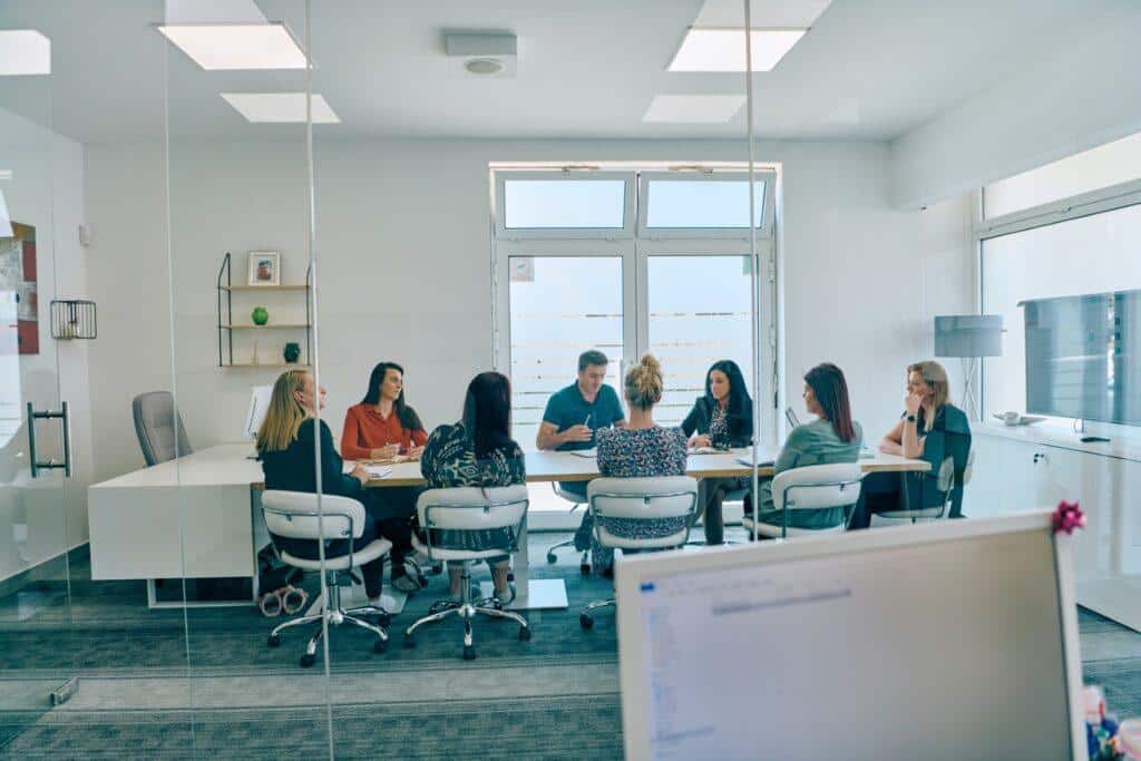Reunión de trabajo en sala de conferencias con varias personas sentadas alrededor de una mesa