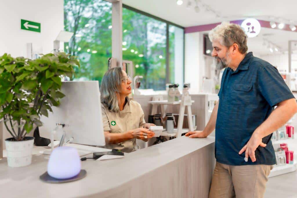 Dependienta atendiendo a cliente en mostrador de tienda de salud y bienestar, ofreciendo productos e información personalizada